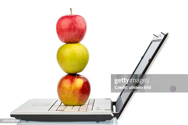 Ein Apfel liegt auf der Tastatur eines Computers. Symbolfoto für gesunden und vitaminreichen Snack.