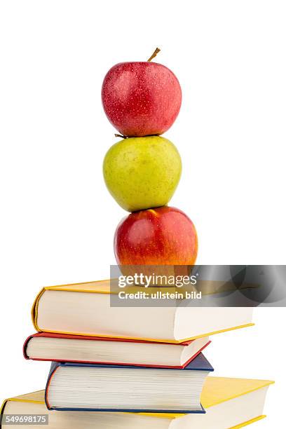 Ein Apfel liegt auf einem Bücherstapel. Symbolfoto für gesunde und vitaminreiche Nahrung in der Schulpause.