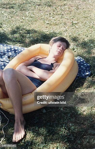 Woman has a nap in a rubber boat on the lawn - 1950s