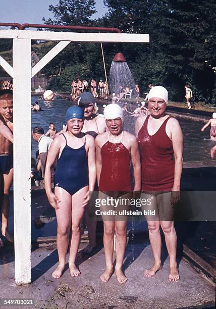 Adult and children take a shower in an open air pool - 1950s