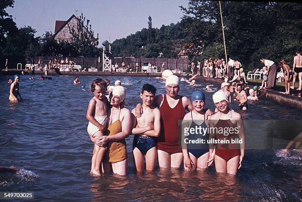 Adult and children pose in an open air pool - 1950s