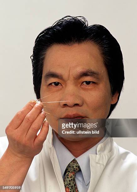 Portrait, Dr. Giac Nguyen, Heilpraktiker, Akupunkteur aus Vietnam, mit verschiedenen Akupunkturnadeln, alte asiatische Heilmethode, Muenchen,