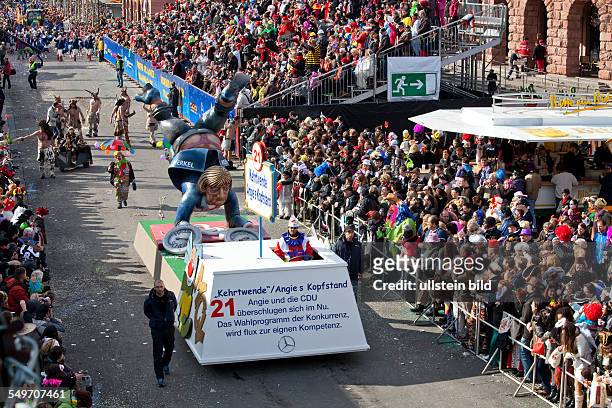 Carnival in Mainz, parade with a sculpture of Chancellor Angela Merkel on a vehicle.