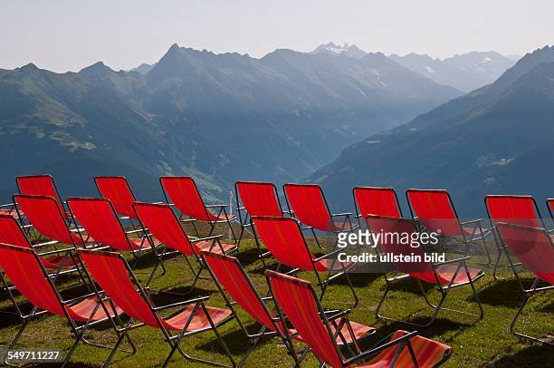 Rote Liegestühle am Penkenjochhaus in 2095 Meter Höhe in den Tuxer Alpen in Tirol in Österreich. Diese Berghütte befindet sich an der Bergstation der...