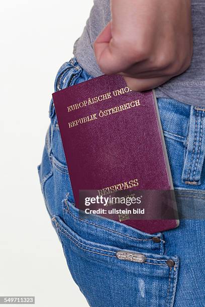 Die Hand einer jungen Frau zieht einen österreichischen Reisepass aus der Tasche ihrer Jeans