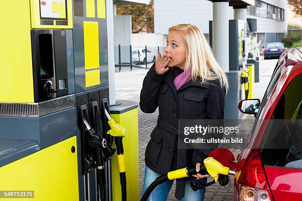 Eine junge Frau Tankbenzin auf einer Tankstelle. Die Kosten für das Auto werden wegen der Benzinpreise immer teurer