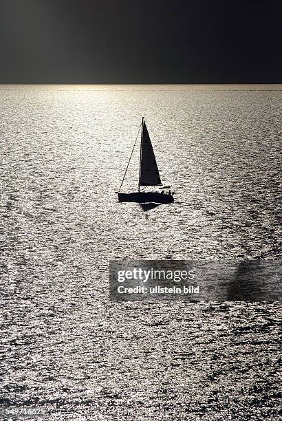 Cap Sani, Greece, a sailboat in the backlight in the Agean Sea