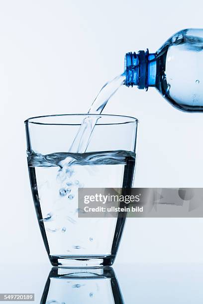 Aus einer Flasche wird Wasser in ein Glas gegossen, Symbolfoto für Trinkwasser, Bedarf und Verbrauch