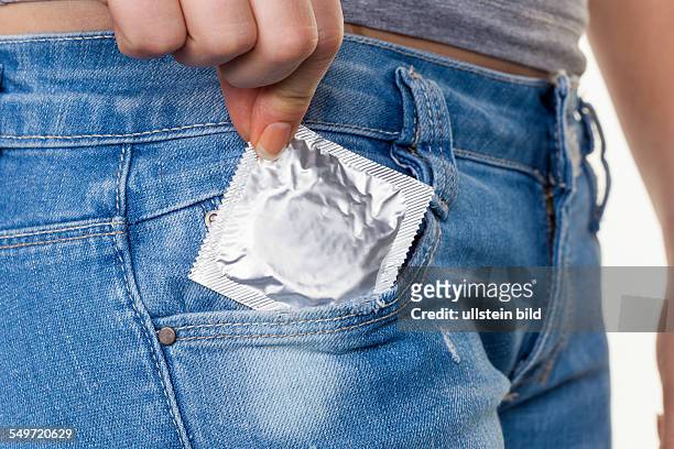 Die Hand einer jungen Frau zieht ein Kondom zur Verhütung einer Schwangerschaft aus der Tasche ihre Jeans