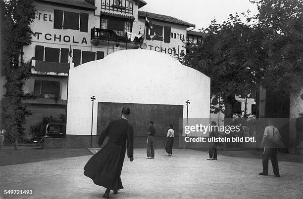 Spain, population: Basque country - men playing Pelota at the wall the basque cross 'Lauburu'