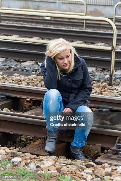 Eine junge Frau ist traurig, ängstlich und deprimiert. Sitzt auf einem Gleis und ist einsam