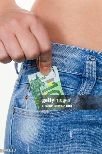 Die Hand einer jungen Frau zieht einen Euro-Geldschein aus der Tasche ihrer Jeans