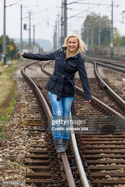 Auf der Suche nach der richtigen Entscheidung balanciert eine junge Frau auf einem Gleis. Das Leben stellt die Weichen.