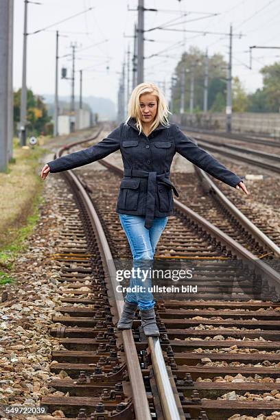 Auf der Suche nach der richtigen Entscheidung balanciert eine junge Frau auf einem Gleis. Das Leben stellt die Weichen.