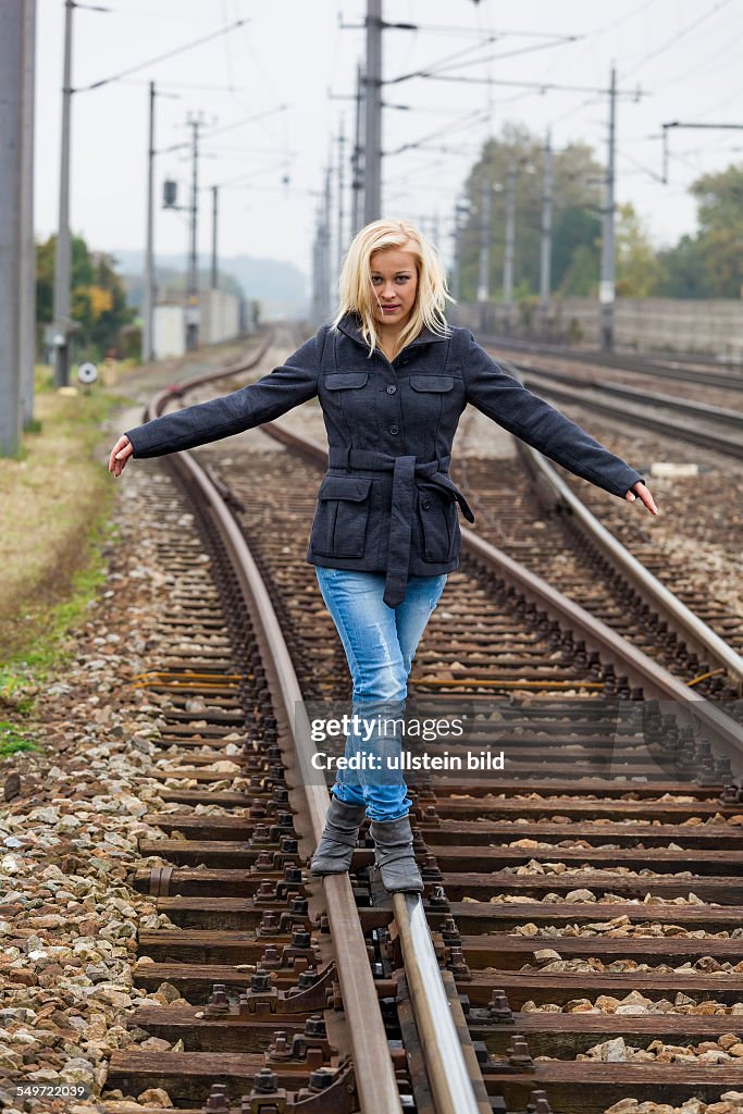 Auf der Suche nach der richtigen Entscheidung balanciert eine junge Frau auf einem Gleis. Das Leben stellt die Weichen.