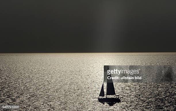 Cap Sani, Greece, a sailboat in the backlight in the Agean Sea