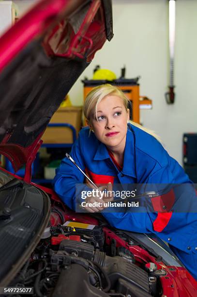 Eine junge Frau als Mechaniker in einer Autowerkstatt. Seltene Berufe für Frauen. Auto wird in Werkstatt repariert