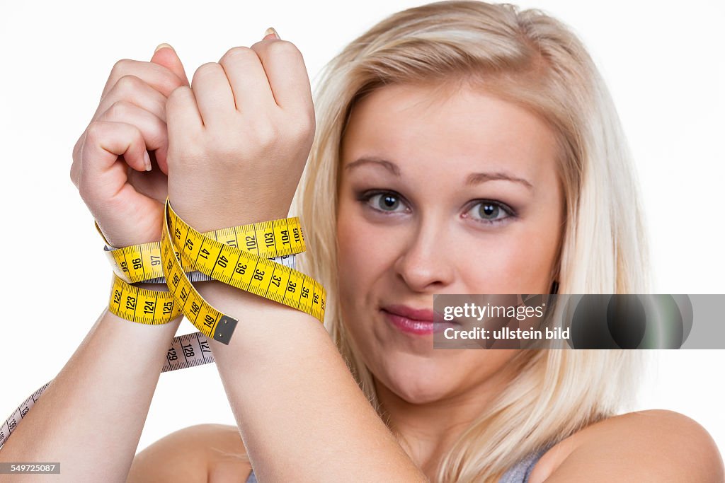Eine junge Frau mit einem Maßband vor der nächsten Diät. Abnehmen und fasten