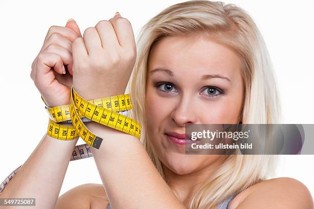 Eine junge Frau mit einem Maßband vor der nächsten Diät. Abnehmen und fasten