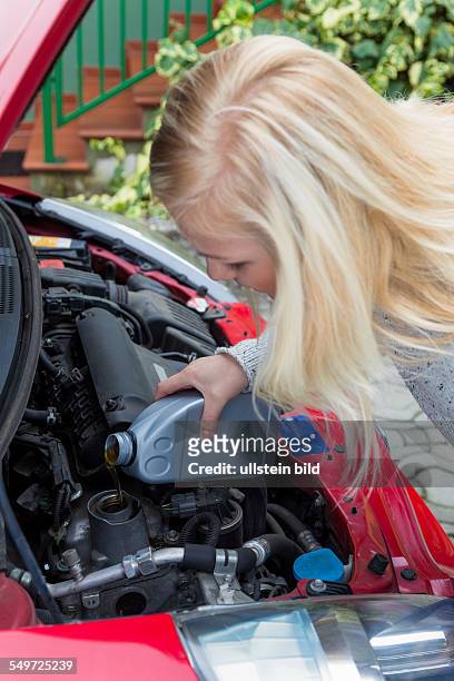 Eine junge Frau füllt Öl in ihrem Auto nach