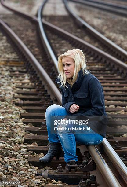 Eine junge Frau ist traurig, ängstlich und deprimiert. Sitzt auf einem Gleis und ist einsam