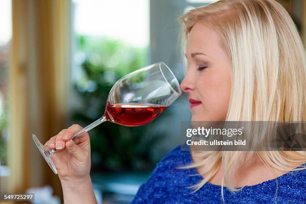 Eine junge Frau bei einer Weinverkostung. Probiert ein Glas Rotwein im Rotweinglas