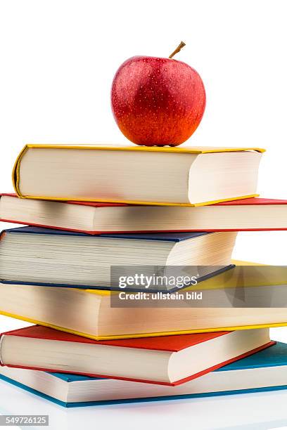 Ein Apfel liegt auf einem Bücherstapel. Symbolfoto für gesunde und vitaminreiche Nahrung in der Schulpause.