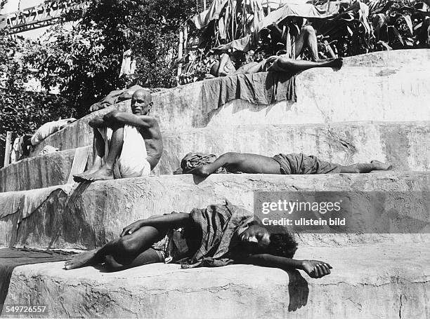 Menschen liegen auf den Stufen am Ufer des Ganges