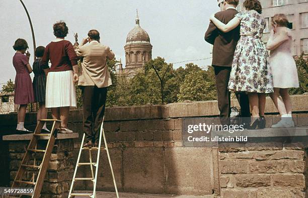 Berlin, Menschen in Kreuzberg nähe Heinrich-Heine-Strasse schauen über die Berliner Mauer in Richtung Ostberlin, hinten die Kirche St. Michael im...