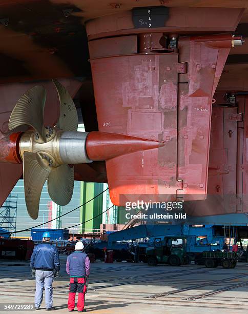Zwei Werftarbeiter betrachten die Schiffschraube und das Ruder des ersten Spezialtransporters fuer die DFDS-Reederei waehrend der Fahrt durch das Tor...