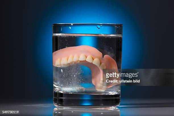Ein Zahnersatz wird in einem Glas mit Wasser gereinigt. Richtige Hygiene.