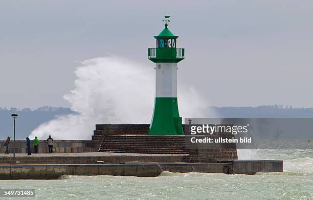 Einige Touristen beobachten eine tosende Welle am Leuchtturm in Sassnitz. In der Hafenstadt au der Insel Ruegen sind 10 Grad und 24 kn Wind aus Ost....