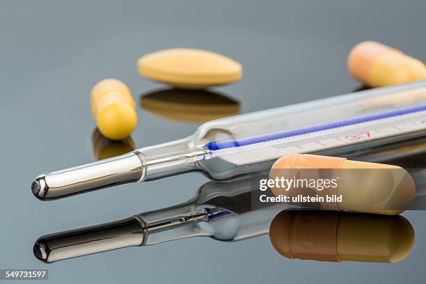 Ein Fieberthermometer und Tabletten. Symbolfoto für Grippe und Erkältungen