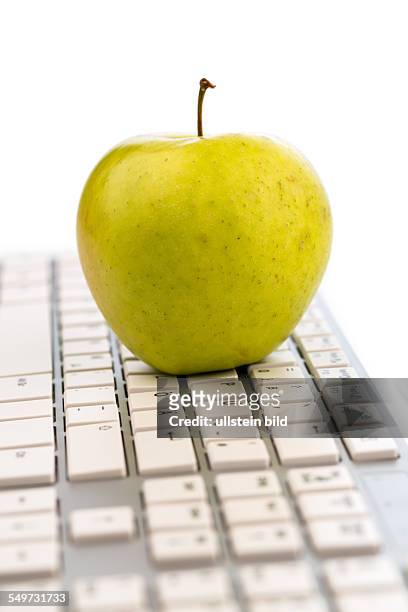 Ein Apfel liegt auf der Tastatur eines Computers. Symbolfoto für gesunden und vitaminreichen Snack.