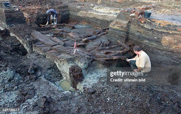 Die Grabungshelfer legen die grossflaechige Holzlage aus der Zeit vor 1250 in der Greifswalder Innenstadt frei. Die Archaeologen graben sich etwa...