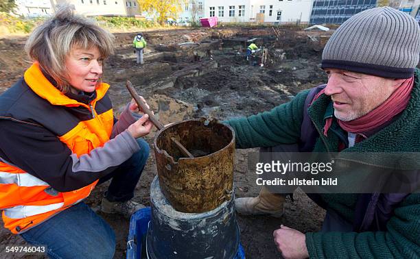 Grabungsleiter diskutieren das gefundene Schoepfgefaess aus Eiche vor der Ausgrabung der grossflaechigen Holzlage aus der Zeit vor 1250 in der...