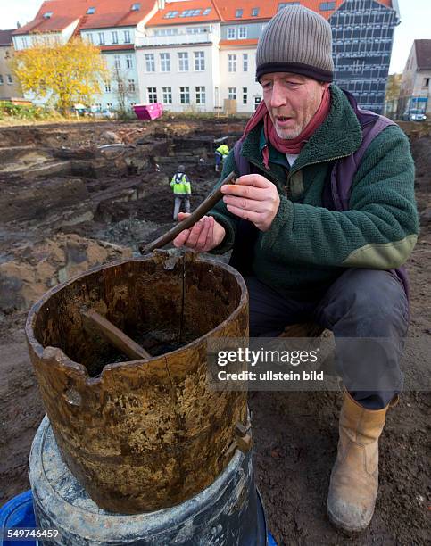 Grabungsleiter Peter Kaute untersucht das gefundene Schoepfgefaess aus Eiche vor der Ausgrabung der grossflaechigen Holzlage aus der Zeit vor 1250 in...