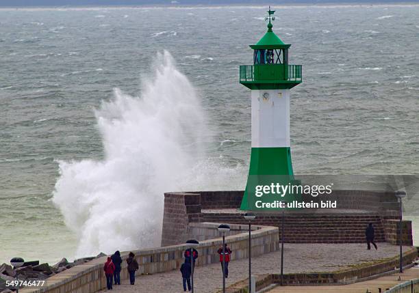 Einige Touristen beobachten eine tosende Welle am Leuchtturm in Sassnitz. In der Hafenstadt au der Insel Ruegen sind 10 Grad und 24 kn Wind aus Ost....