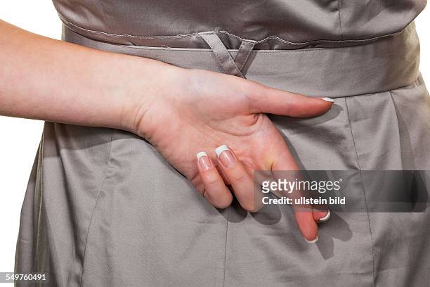 Die gekreuzten Finger einer Frau. Steuerhinterziehung, Lügen, Betrug
