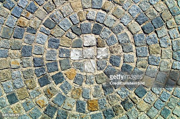 Pflastersteine aus Granit auf einem Platz wurden in Kreisen verlegt. In der Mitte ein Kreuz