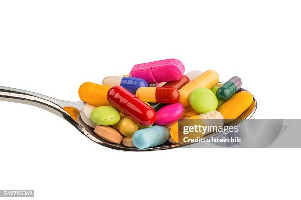 Viele bunte Tabletten auf einem Löffel. Symbolfoto für Tablettensucht und Mißbrauch von Medikamenten.