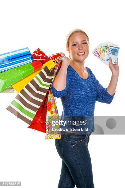 Eine junge Frau kommt mit vielen Einkaufstaschen vom Shopping zurück. Mit Euro Geldscheinen