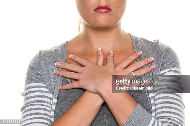 Eine junge Frau hält ihre Hände vor ihren Körper. Symbolfoto für Schutzbedürfnis, Unsicherheit und Nachdenklichkeit