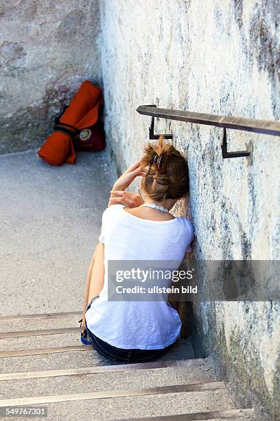 Eine junge Frau sitzt traurig und einsam auf einer Treppe.