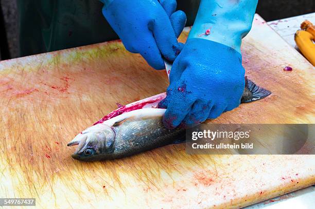 Ein Fisch auf einem Fischmarkt wird vom Fischer filetiert