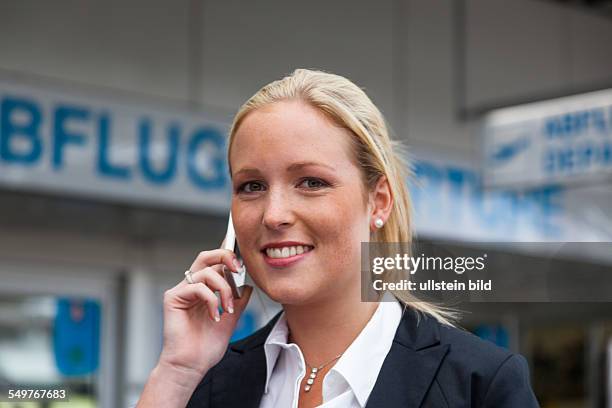 Eine Geschäftsfrau telefoniert mit ihrem Handy am Flughafen. Roaminggebühren bei Smartphones im Ausland
