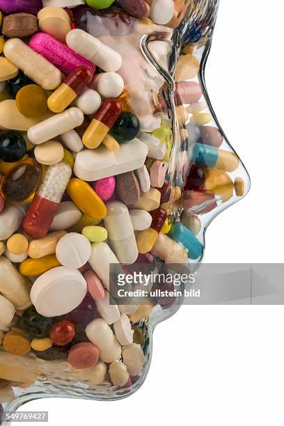 Ein Kopf aus Glas mit vielen Tabletten gefüllt. Symbolphoto für Medikamente, Mißbrauch und Tablettensucht.