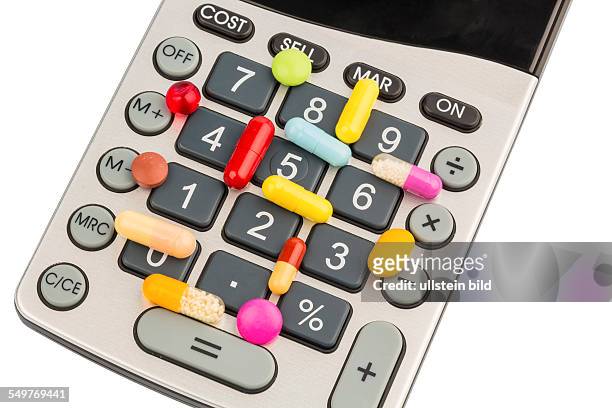 Tabletten liegen auf einem Taschenrechner. Symbolfoto für Kosten in der Medizin und Pharmaindustrie