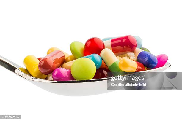 Viele bunte Tabletten auf einem Löffel. Symbolfoto für Tablettensucht und Mi�ßbrauch von Medikamenten.