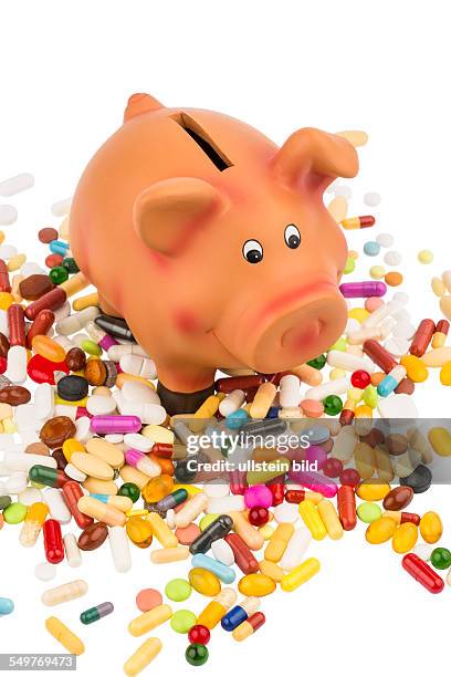 Tabletten liegen neben einem Sparschwein. Symbolfoto für Kosten in der Medizin und Pharmaindustrie